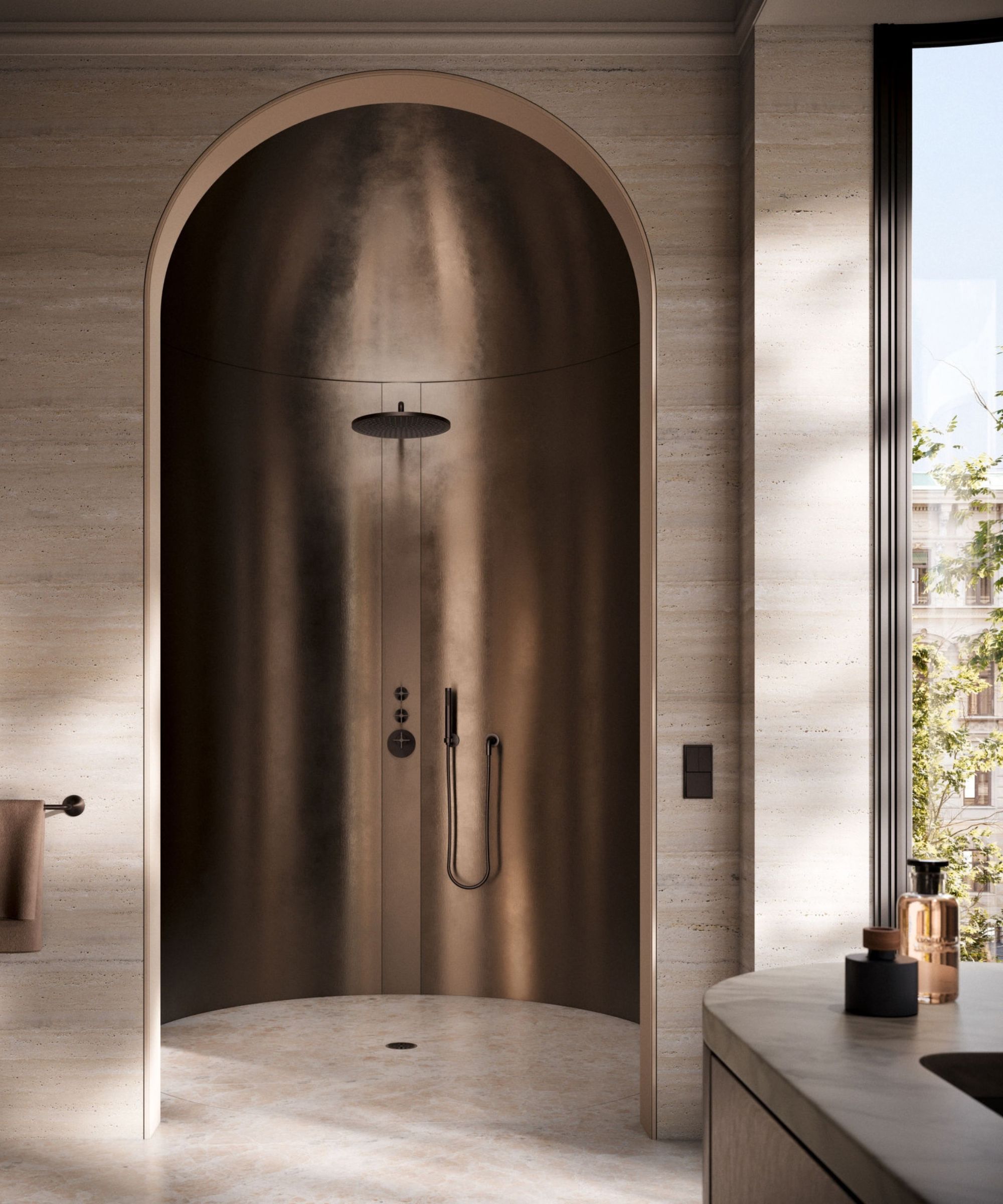 A sculptural attic bathroom finished entirely in warm blush-toned plaster, with a sloped ceiling and roof light. A black-framed glass shower enclosure houses a ceiling rain head and matte black controls, beside a built-in white bath with black taps and a ladder-style black heated towel rail.