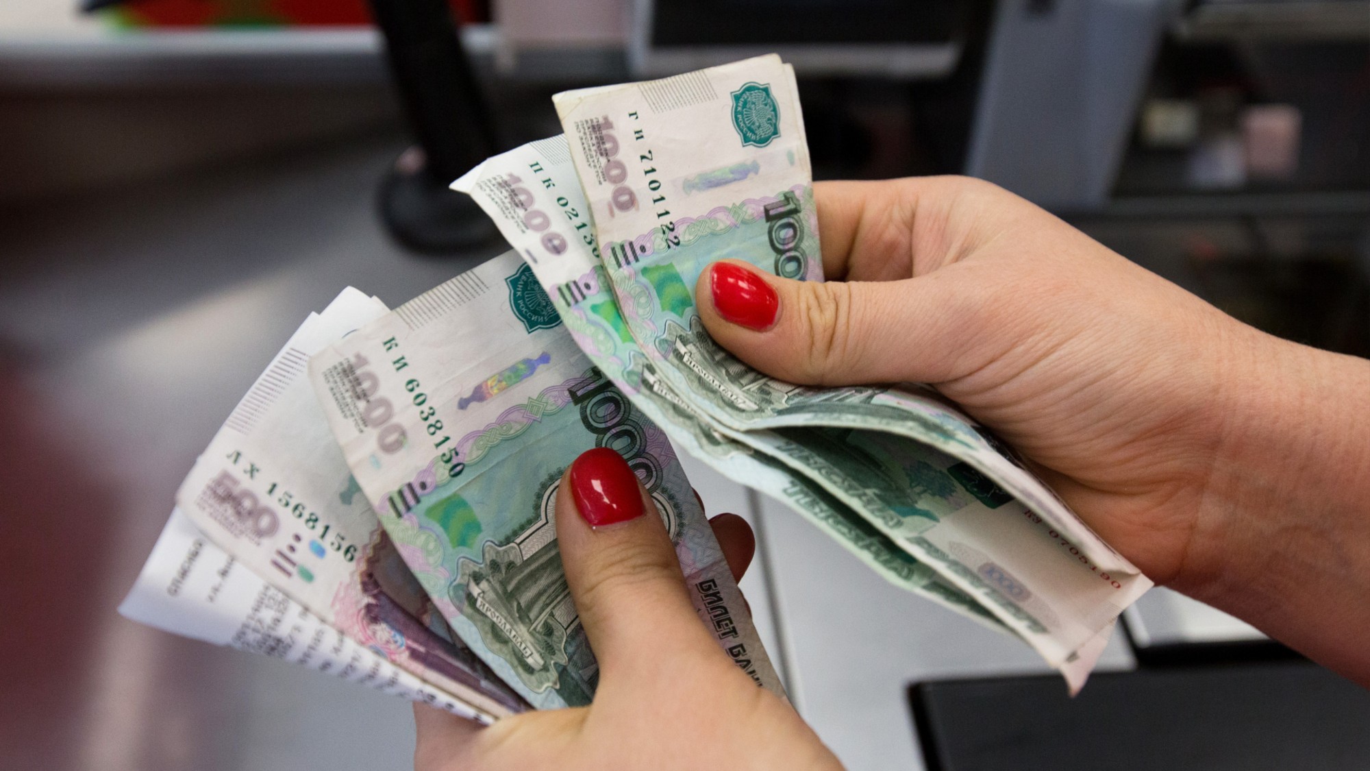 A woman counts Russian ruble banknotes at a store in Moscow.