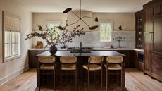 A kitchen with wooden cabinets, a black island, and white walls