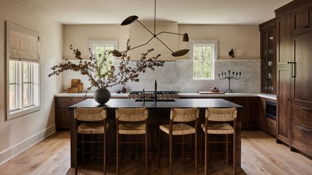 A kitchen with wooden cabinets, a black island, and white walls