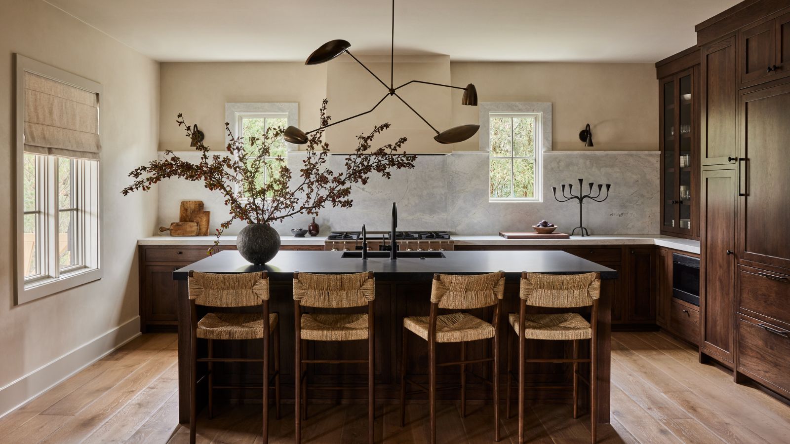A kitchen with wooden cabinets, a black island, and white walls