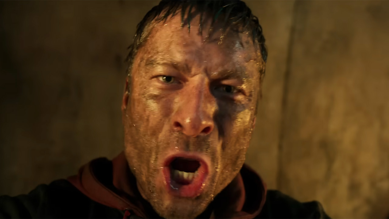 Glen Powell yelling into a camera closeup, covered in dirt in The Running Man.