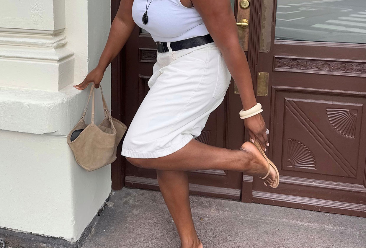 Woman wearing heeled tan flip-flops with white Bermuda shorts and a white tank.