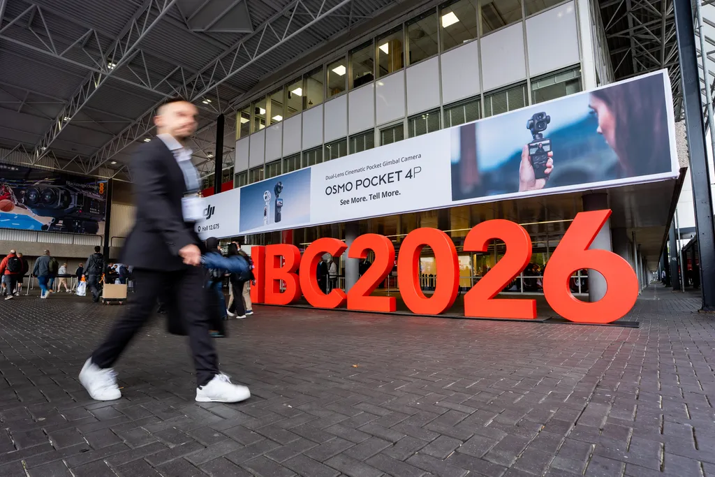 Man walking past a sign saying IBC2026