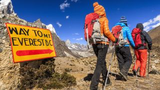 Three hikers passing a sign for Everest Base Camp