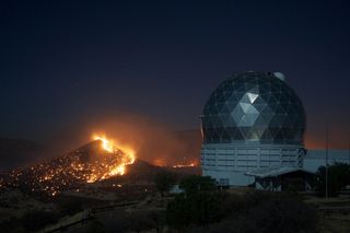 At the McDonald Observatory in West Texas, the nearby Guide Peak can be seen on fire and almost completely burned on April 17, 2011 during a series of severe wildfires in the region. The observatory's Hobby-Eberly Telescope is visible at right.