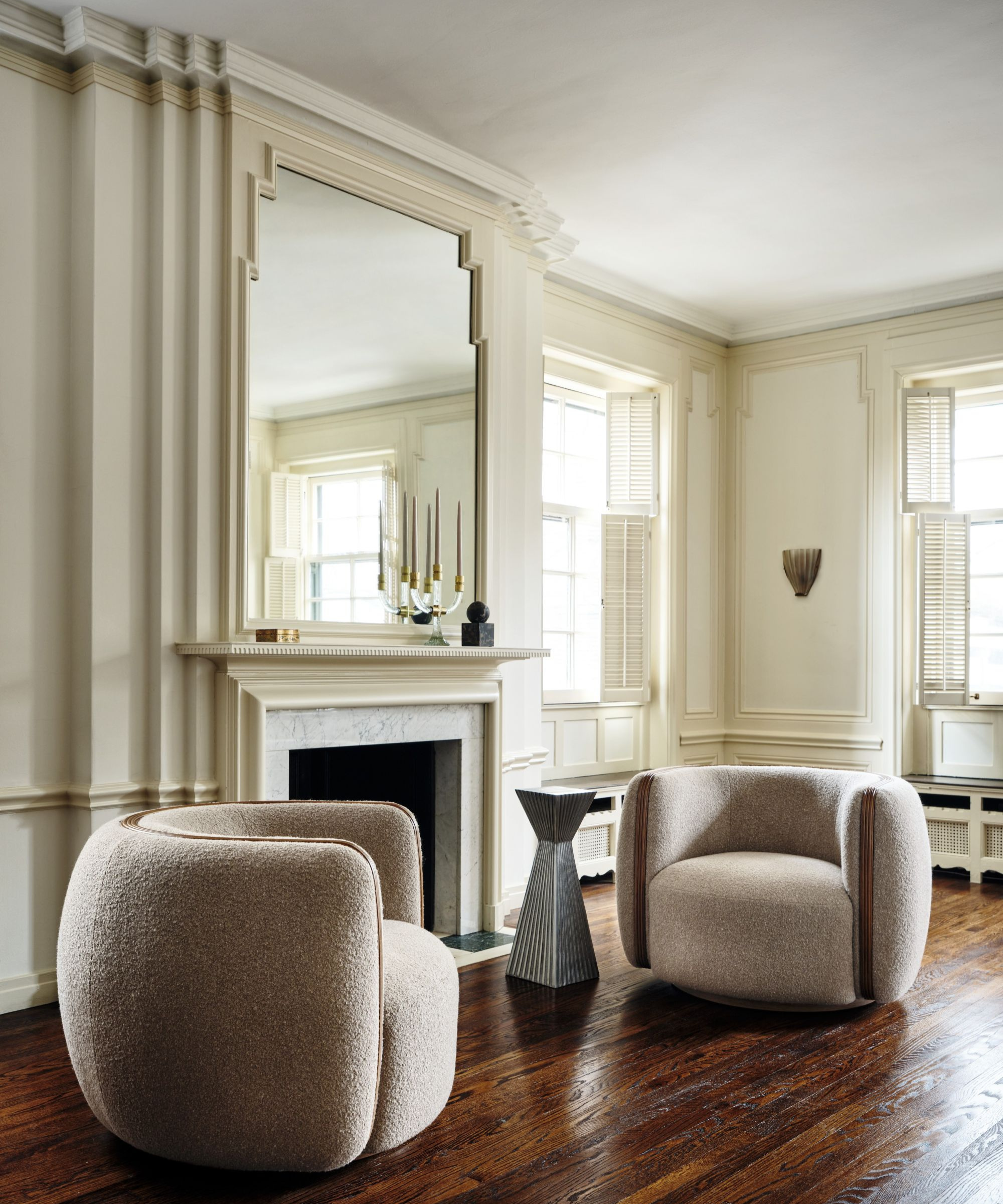 a sitting room with two chairs, a geometrically shaped drink table, and a fireplace
