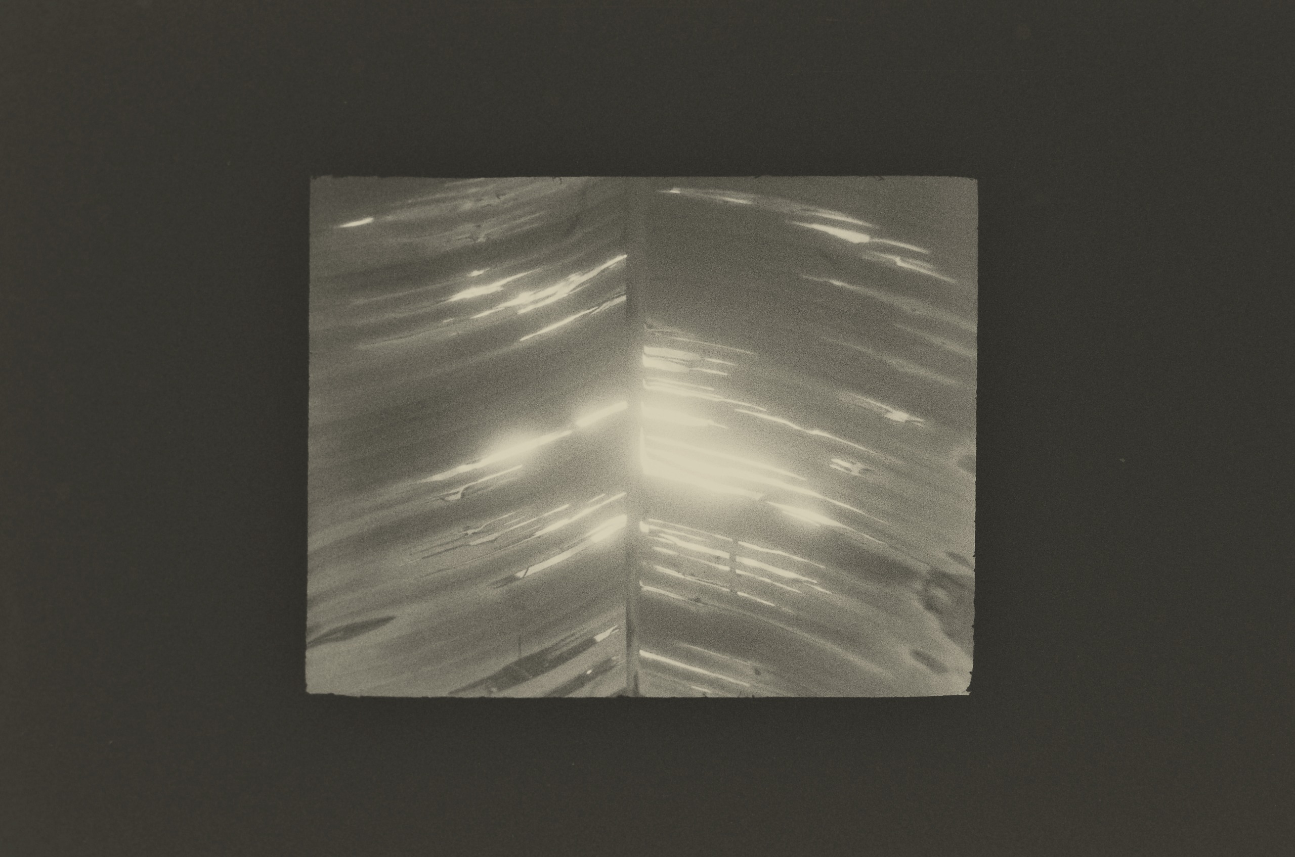 A black-and-white print by Jing Huang of bright streaks of light rippling across a curved, glossy surface, divided down the middle by a thin vertical line.