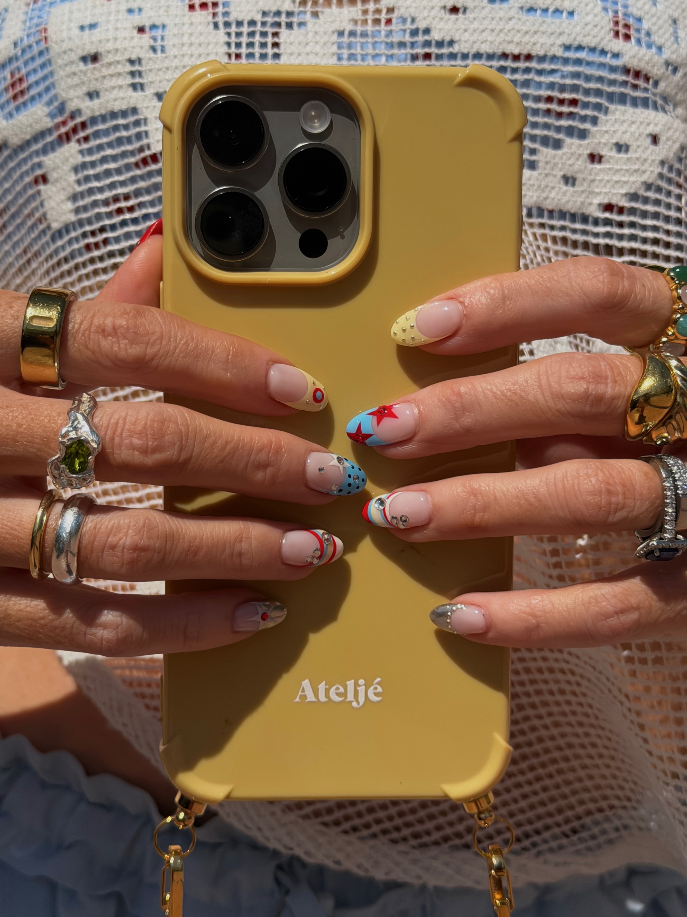 A close-up of turquoise, yellow and red spot and stripe nail art