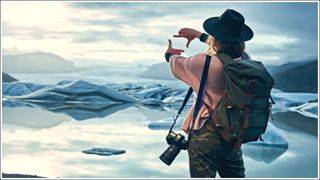 Young woman making photos of beautiful glacier