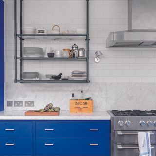 Bright blue kitchen with white metro tiles on entire wall.