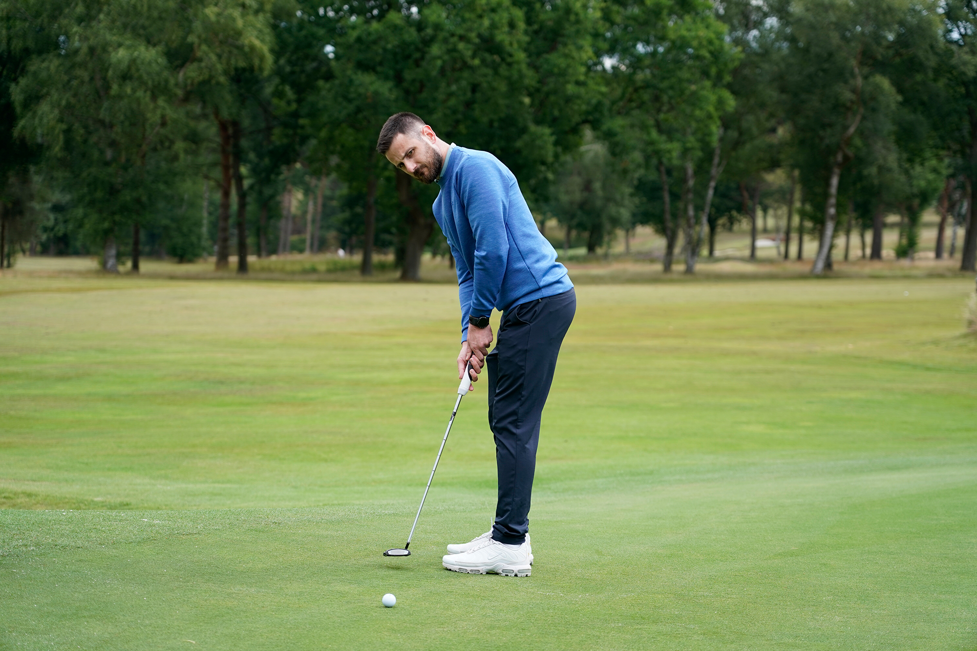 Baz Plummer hitting a putt on the fourth green at Sand Moor Golf Club, watching the ball roll towards the target
