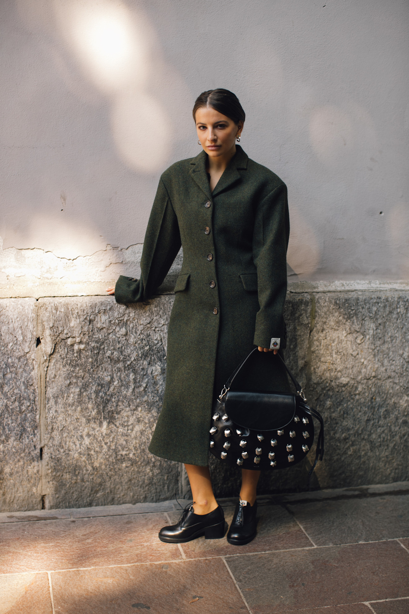 Woman in green coat and decorated bag.