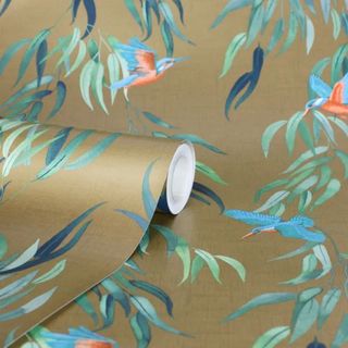 Close up of a roll of wallpaper that's gold with birds and green laves all over