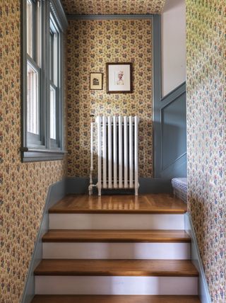 A wallpapered stairwell with bold light blue trim and paneling