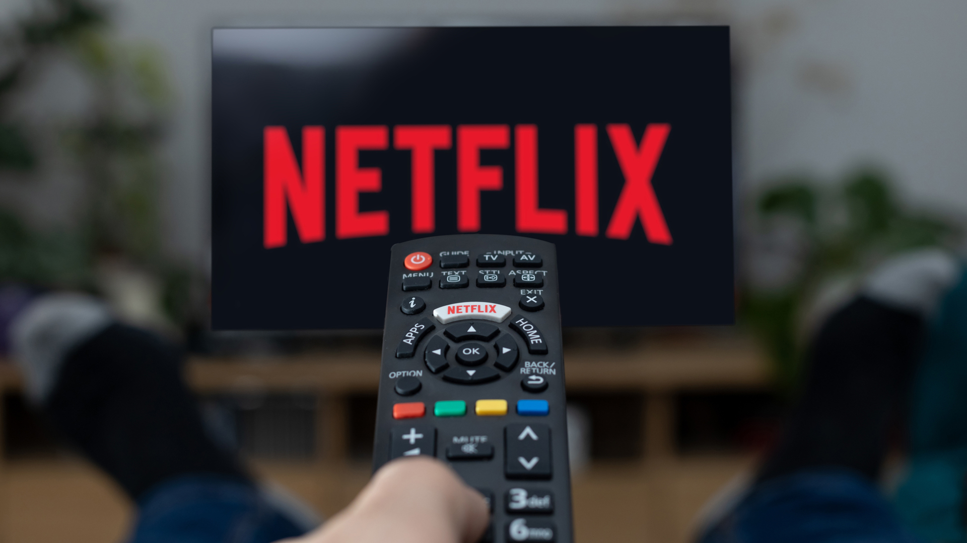 Рекламное изображение человека, который смотрит Netflix по телевизору с пультом в левой руке