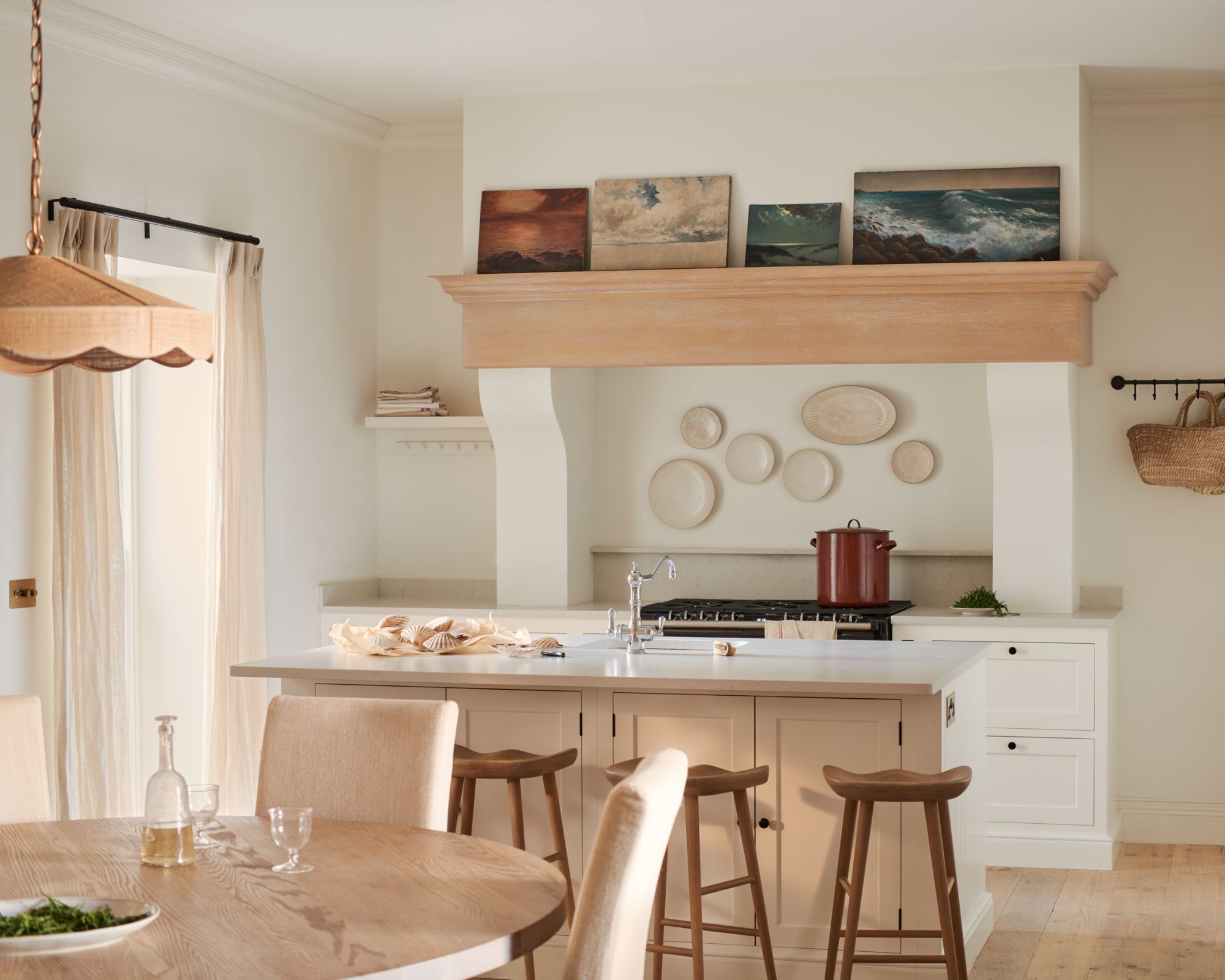 A white and cream kitchen with paintings above the rangehood