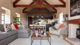 interior of open plan living room, kitchen and dining room space with large wooden exposed ceiling beams and fireplace