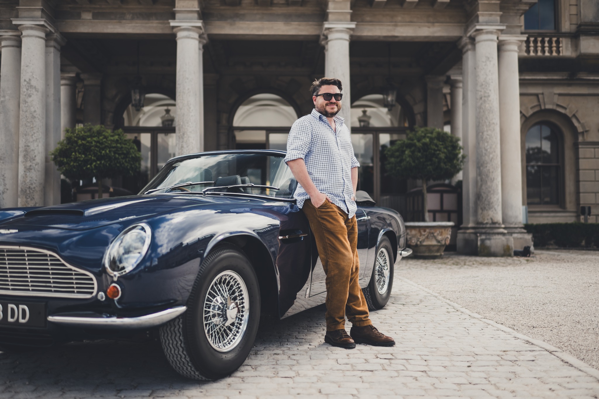 the author Adam Hay Nicholls stands in front of an Aston Martin DB6 volante