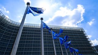 The EU flags flutter in the wind in front of the Berlaymont, the EU Commission headquarter on June 16, 2023 in Brussels, Belgium. The Flag of Europe, adopted on December 9, 1955, is a flag decorated with twelve five-pointed gold stars, one of the points pointing upwards, arranged at equal distance in a circle on a field of azure. It represents solidarity and union between the peoples of Europe.