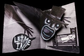 The Babadook pop-up book with 'let me in' contained within a speech bubble.