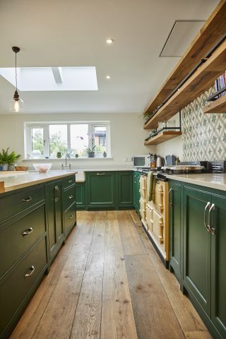 green and white kitchen with green units and white walls, tiled green splash back wooden floorboards