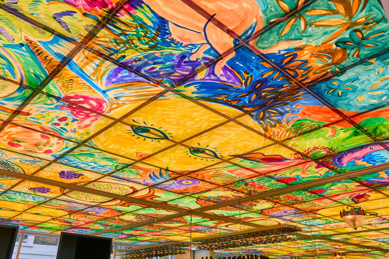 A whimsical mural depicting fantastical creatures adorn the ceiling of a 70s-inspired wine bar and ice cream parlor.