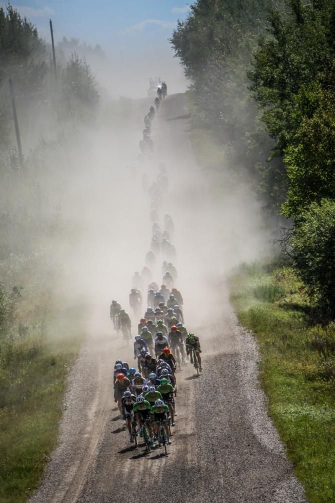 The peloton gets strung out through the dust