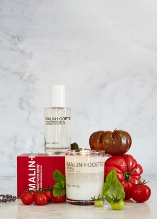 A stages photo of a candle and room spray surrounded by tomatoes