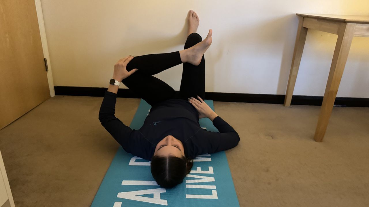 Fitness writer Daniella Gray doing reverse pigeon wall Pilates move at home