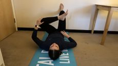 Fitness writer Daniella Gray doing reverse pigeon wall Pilates move at home