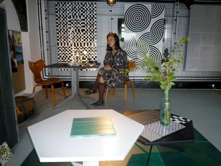 A woman sitting down crossed legs at the design display section for Danish tile company Made a Mano