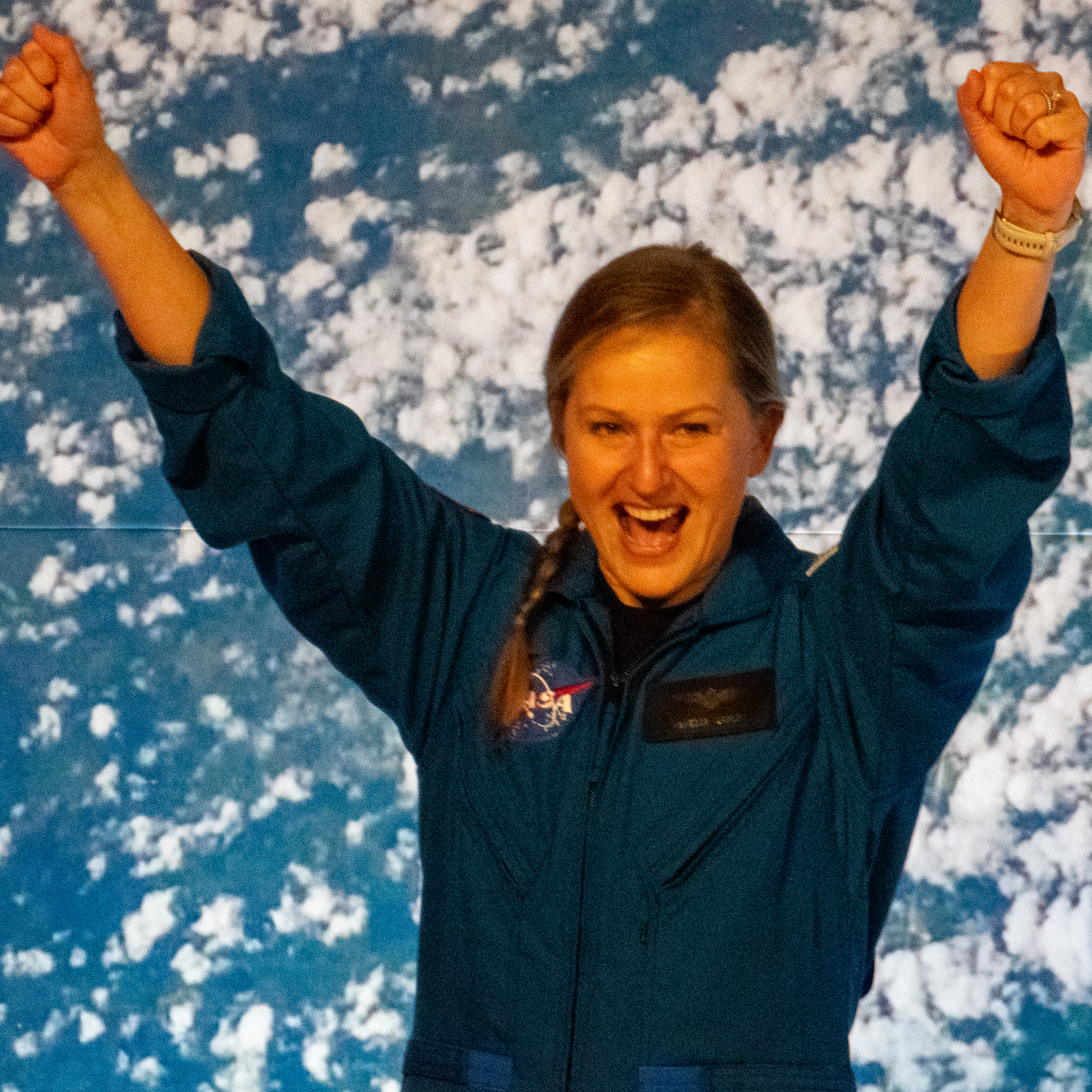 people in blue jumpsuits smile and wave.