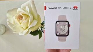 Huawei Watch Fit 3:n myyntipaketti ja ruusu vaalean pöydän päällä