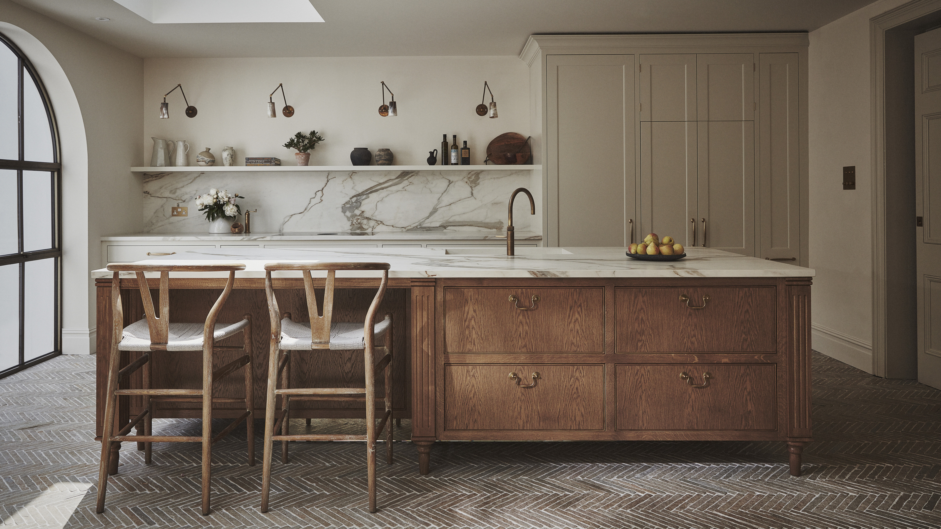 A modern minimalist kitchen with a large wood and marble island and open shelving over the sink