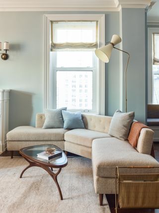 light blue living room with cream couch and orange throw