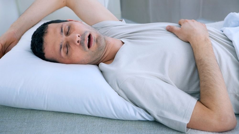 A man laying in bed snoring 