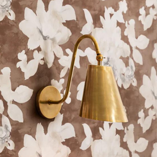 A gold sconce hanging over bright wallpaper.