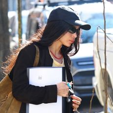 Zo&euml; Kravitz wearing a black cardigan, baseball cap, and hat with khaki jeans in NYC
