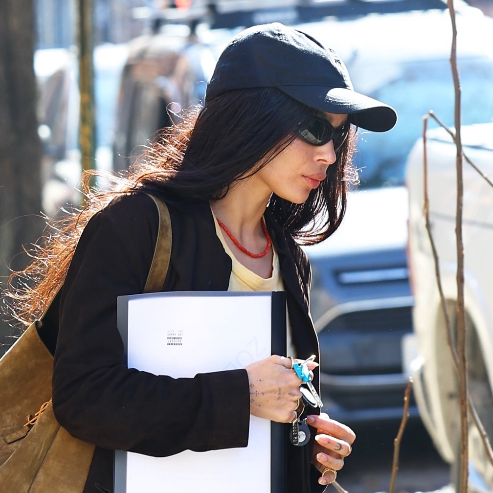 Zo&euml; Kravitz wearing a black cardigan, baseball cap, and hat with khaki jeans in NYC