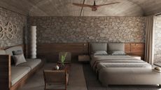 A natural bedroom with stone walls, wooden accents and gray bedding