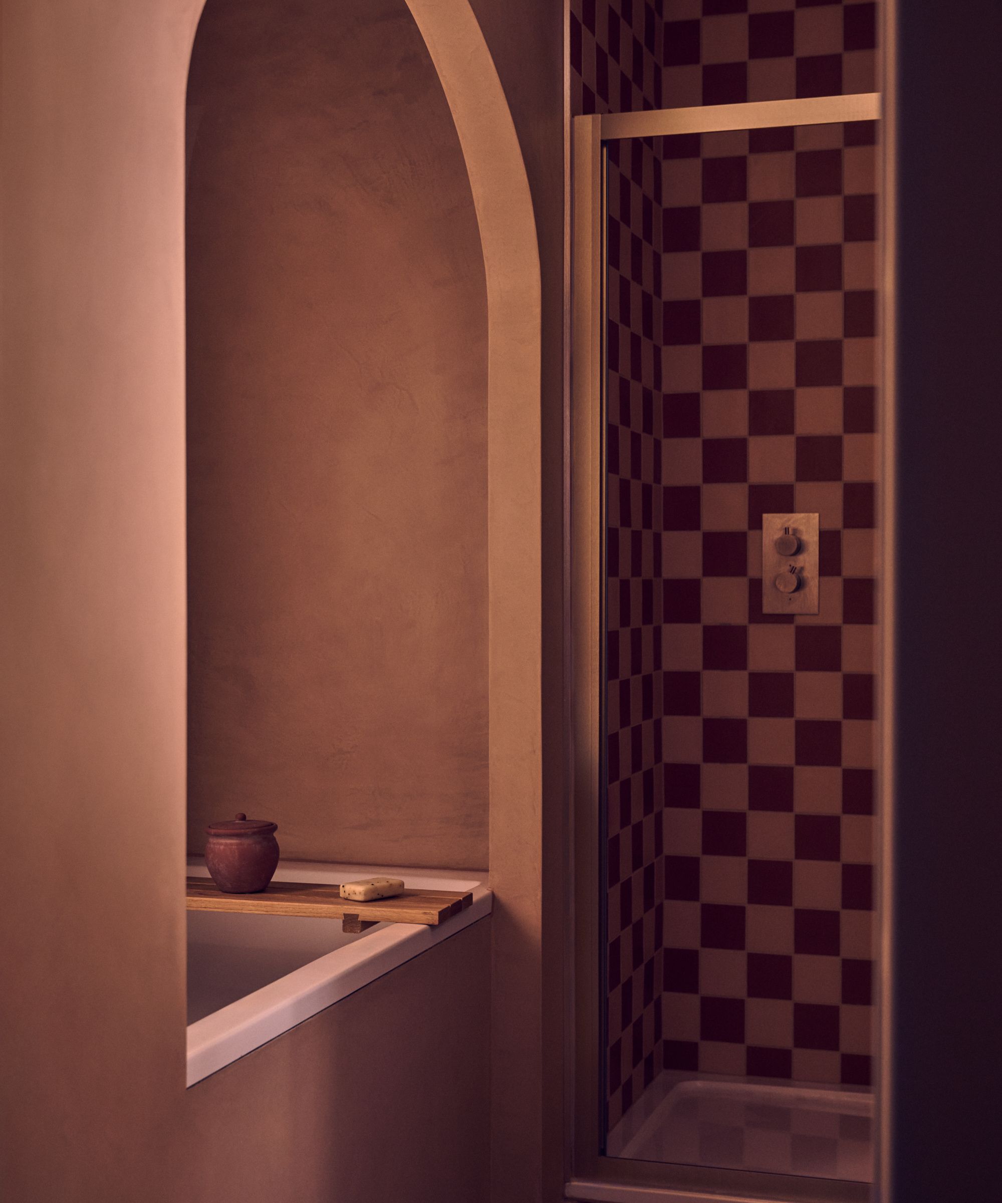 A bath nook with an arched doorway and microcement walls