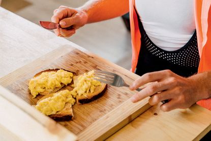 A female cyclist eating a plate of food packed with protein and vegetables to help prevent muscle pain