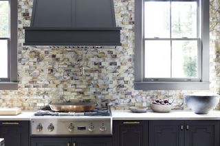 Kitchen with dark cabinets and shell style backsplash behind range