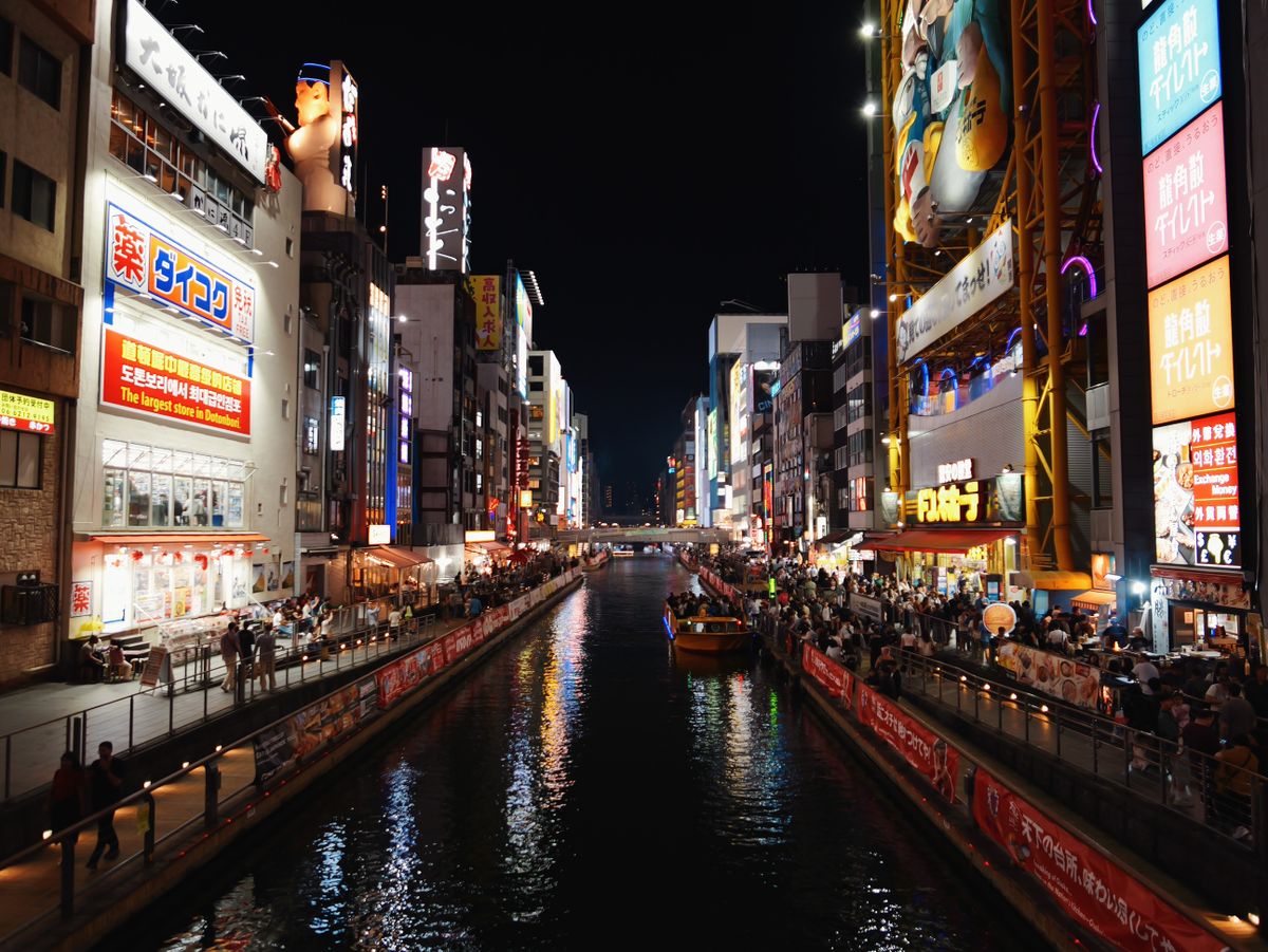 Night view of Osaka&rsquo;s Dotonbori canal lined with illuminated signs.