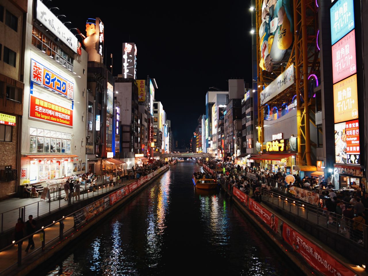 Night view of Osaka&rsquo;s Dotonbori canal lined with illuminated signs.