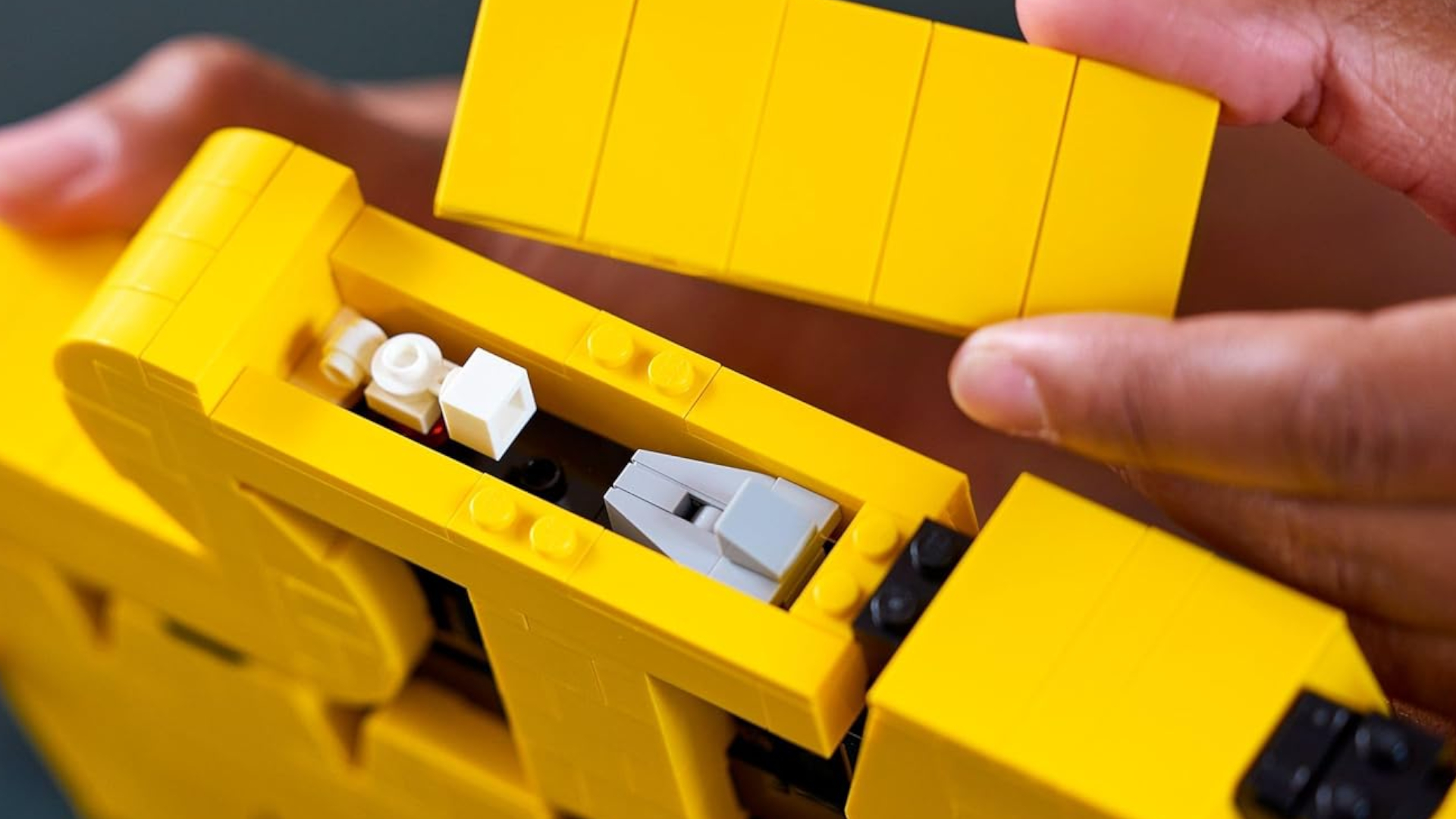 A hand pulls a yellow panel off the Star Wars logo model to reveal two little ships inside