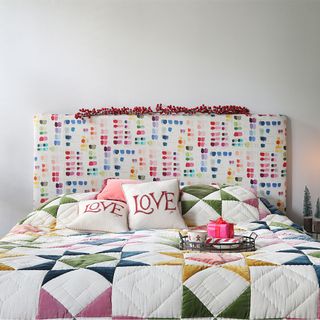 colourful bedroom with upholstered headboard and patchwork bedspread