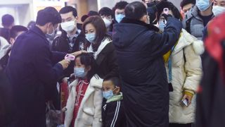 Staff members check the body temperature of passengers after a train from Wuhan arrived at Hangzhou Railway Station in Hangzhou, China.