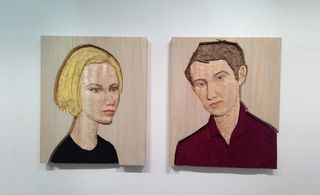 A pair or wood carvings, left: a woman with blonde hair and dark shirt; right - a man in a dark red shirt.